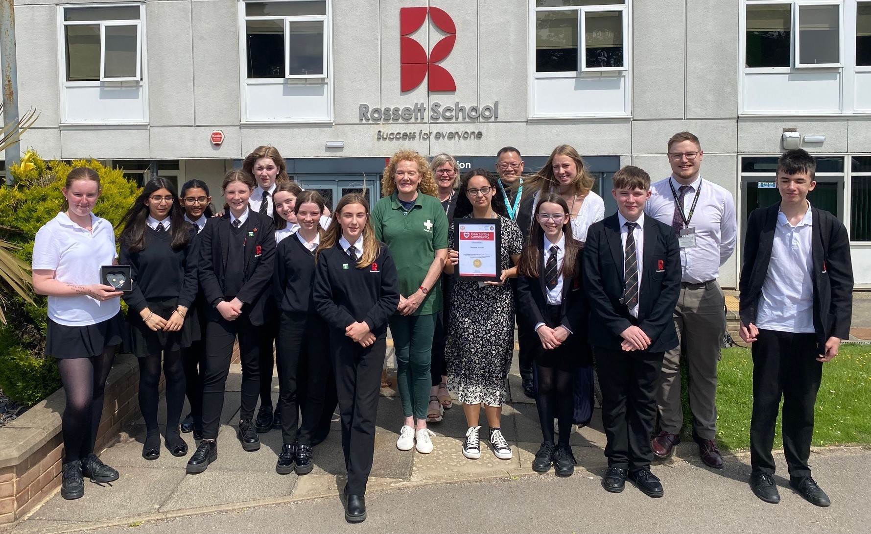 School students and staff receiving an award from ambulance service representatives